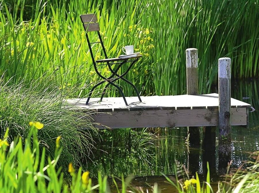Складной стульчик на деревянном мостике у пруда